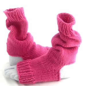 Puede incluir: Un par de polainas de punto rosa con un puño doblado. Las polainas están hechas de un hilo suave y peludo.