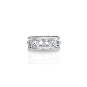 Op de afbeelding: Een zilveren ring met een herhalend patroon van in elkaar grijpende cirkels en een bit-ontwerp.