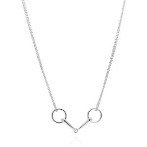 Peut inclure: Un collier en argent avec une double chaîne et un pendentif en forme de mors de cheval.