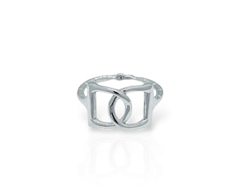 Puede incluir: Un anillo de plata con un diseño de doble bucle. El anillo está hecho de metal liso y pulido y tiene un estilo simple y moderno.