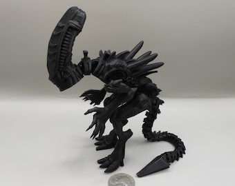 May include: Black plastic articulated action figure of an alien creature with a long tail and a large head. The figure is posed in a crouching position with its head tilted down.