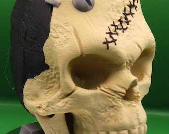 May include: A beige and black skull sculpture with stitched seams and a screw in the forehead. The skull is sitting on a gray base.