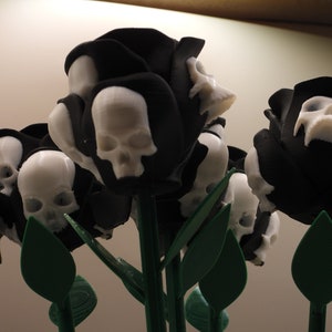 May include: A bouquet of black roses with white skull details. The roses are made of 3D printed plastic and have green stems and leaves.