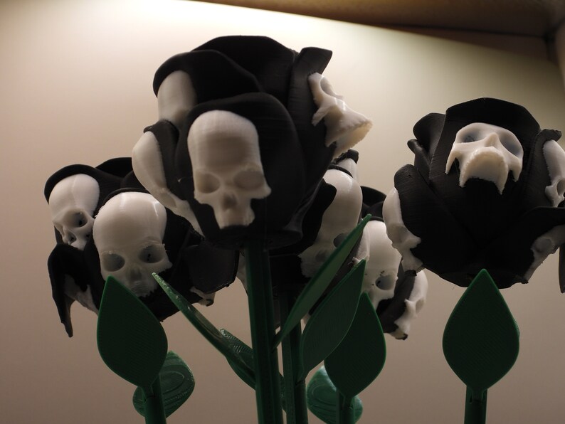 May include: A bouquet of black roses with white skull details. The roses are made of 3D printed plastic and have green stems and leaves.