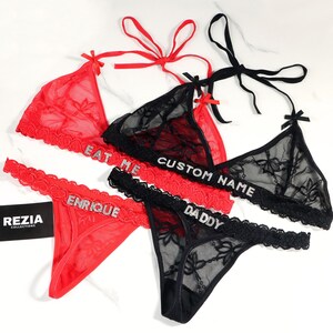 May include: Red and black lingerie sets with lace detailing. The red sets have the text "EAT ME" and "ENRIQUE" in rhinestones. The black sets have the text "CUSTOM NAME" and "DADDY" in rhinestones. Each set includes a top and bottom.