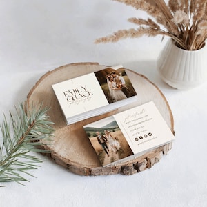 May include: A business card with a white background and brown text. The card features a photo of a couple in a field and the text "Emily Grace Photography". The back of the card has contact information and social media icons.