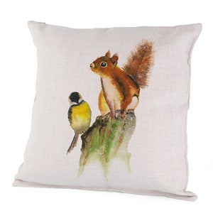 May include: A white throw pillow with a watercolor illustration of a red squirrel and a yellow bird perched on a tree stump.