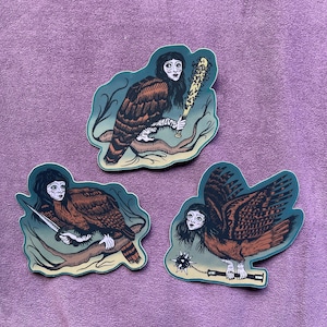May include: Three stickers featuring a creature with a human face and bird-like body. Each sticker depicts the creature holding a weapon: a bat, a knife, and a spiked mace. The stickers have a teal border and are set against a purple background.