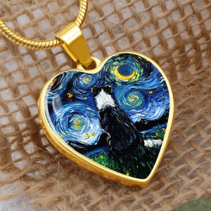 May include: Gold-toned heart-shaped pendant necklace featuring a painting of a black and white dog against a starry night sky, reminiscent of Van Gogh's style. The pendant hangs from a gold chain.