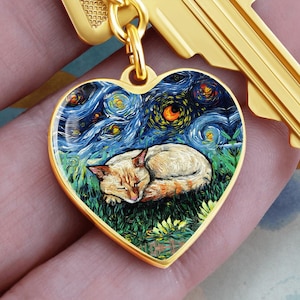 Può includere: Ciondolo a forma di cuore dorato con un gatto addormentato in un campo erboso sotto un cielo stellato. Il ciondolo è attaccato a una catena e una chiave dorate. L'opera d'arte è nello stile di Van Gogh.