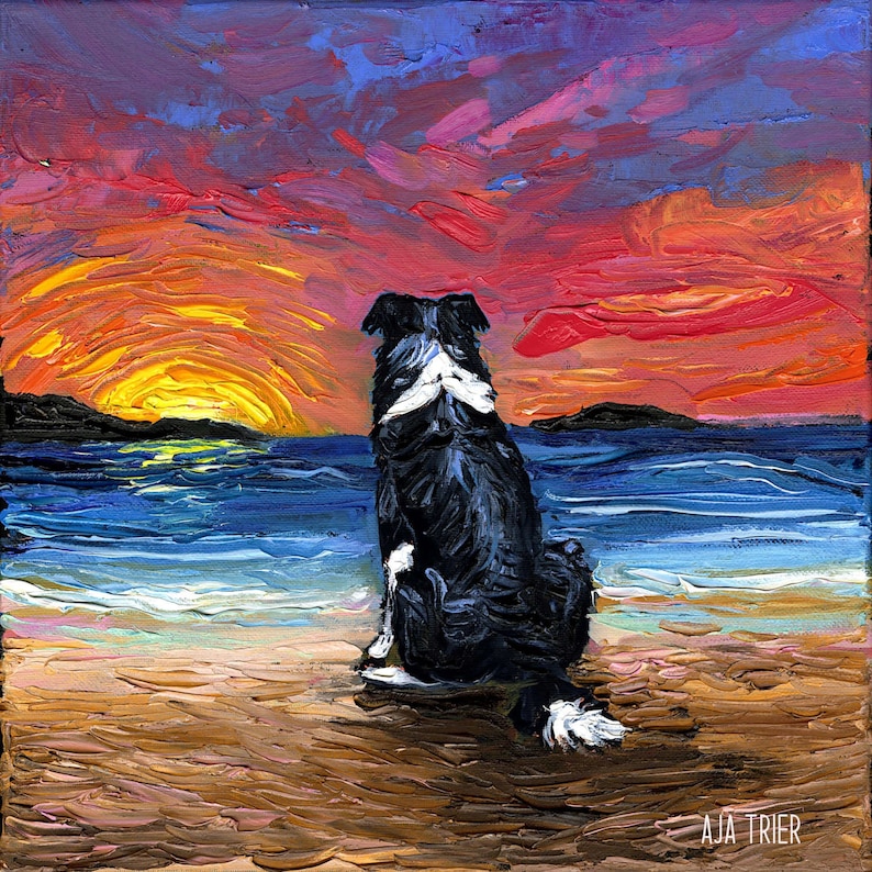 May include: A black and white border collie dog sits on a sandy beach, looking out at a colorful sunset over the ocean. The sky is a mix of orange, red, and purple.