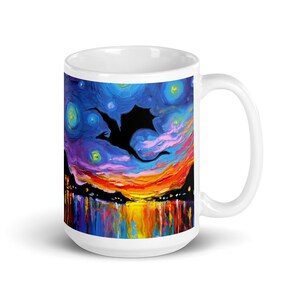 May include: White ceramic mug with a colorful painting of a black silhouette of a dragon flying over a sunset with a starry night sky. The mug has a handle on the right side.