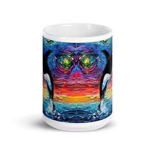 K&ouml;nnte beinhalten: Wei&szlig;e Keramik-Kaffeetasse mit einem farbenfrohen abstrakten Gem&auml;lde von zwei Orcas, die aus dem Wasser springen. Das Gem&auml;lde zeigt einen Regenbogen an Farben, darunter Rot, Orange, Gelb, Gr&uuml;n, Blau und Lila.