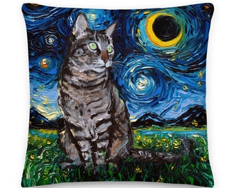 May include: A square throw pillow featuring a thick, textured oil painting style print of a grey tabby cat sitting in a green field. The background depicts a swirling dark blue night sky with a bright yellow crescent moon and glowing stars.