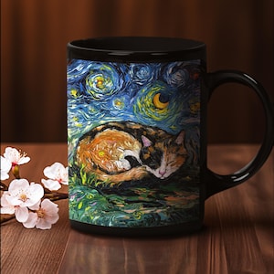 May include: Black ceramic mug with a colorful painting of a calico cat sleeping on a green field under a starry night sky. The painting is reminiscent of Vincent van Gogh's Starry Night.