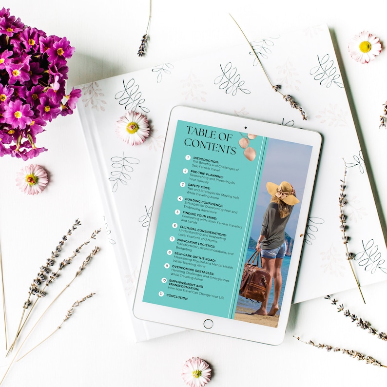 May include: A tablet computer displaying a table of contents for a guidebook on solo female travel. The guidebook covers topics such as pre-trip planning, safety, building confidence, finding your tribe, cultural considerations, navigating logistics, self-care, overcoming obstacles, empowerment, and transformation. The tablet is on a white surface with flowers and lavender.