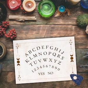 May include: A vintage-style Ouija board with the alphabet, numbers, and the words "YES" and "NO" printed on it. The board is surrounded by candles, a crystal ball, and other mystical items on a wooden surface.