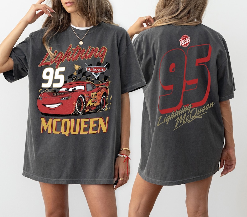 May include: Dark gray t-shirt featuring Lightning McQueen from the Cars movie. The front graphic includes the text "Lightning 95 McQueen" with a red race car. The back of the shirt displays a large "95" and "Lightning McQueen" in red.
