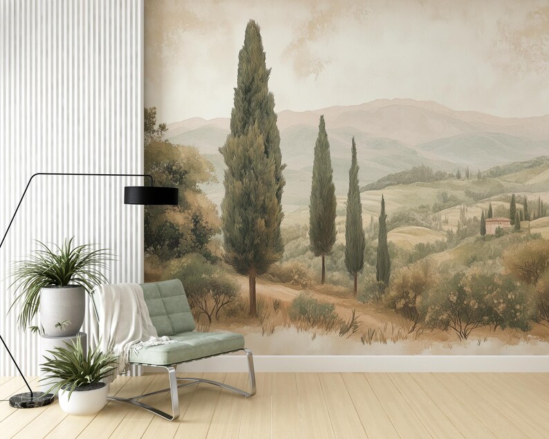 May include: A watercolour painting of a Tuscan landscape with rolling hills, green trees, and a small house in the distance. The painting is framed and hanging on a white wall.