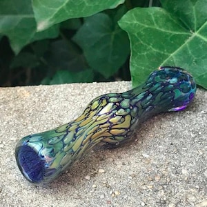 May include: A glass pipe with a swirling pattern of green, blue, and gold. The pipe is about 5 inches long and has a rounded bowl.