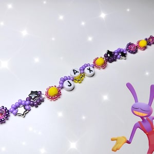 May include: A beaded bracelet featuring purple and pink seed beads, yellow flower-shaped beads, silver star charms, and white letter beads spelling JAX. A purple cartoon rabbit character with yellow gloves and red overalls is positioned below the bracelet.