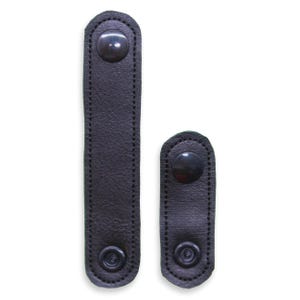 May include: Two black leather snap extensions. One is long and rectangular, the other is shorter and oval-shaped. Both have a snap closure at each end and are stitched around the edges.