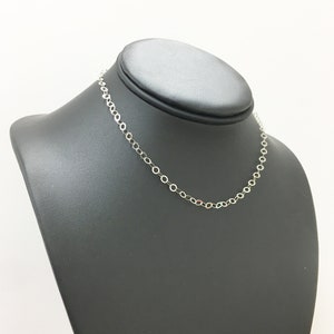 Puede incluir: Un collar de cadena de plata en un expositor negro. La cadena est&aacute; hecha de peque&ntilde;os eslabones redondos.