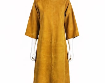 May include: Mustard-colored dress with a boat neckline and three-quarter sleeves. The dress is knee-length and displayed on a white mannequin. The fabric appears to be suede or a suede-like material.