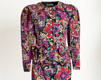 May include: A black and multi-colored floral print skirt suit with a peplum jacket. The jacket has a button closure and the skirt is knee-length.