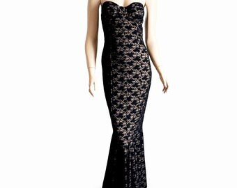 May include: A black strapless lace gown on a mannequin. The dress features a sweetheart neckline and a fitted bodice that flares out at the bottom. The lace overlay is black, and the lining is a neutral color.