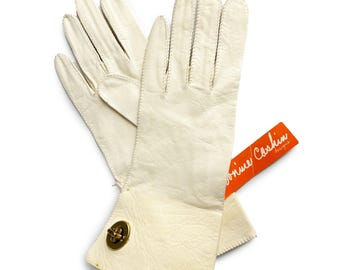 May include: A pair of white leather gloves with a gold button closure. The gloves have a label that reads "Ronnie Coslin Designs".