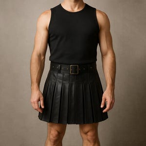 May include: Black leather kilt with pleats and a matching belt with a square buckle. The kilt is paired with a black tank top. The overall look is a blend of traditional and modern styles.