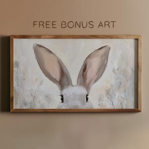 May include: A framed painting of a rabbit's face with large, soft ears. The rabbit is looking directly at the viewer with a gentle expression. The background is a soft, muted palette of beige and white.