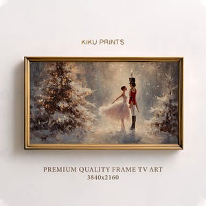 Op de afbeelding: Een ingelijste print met een winterse scène met een ballerina en een notenkraker. De ballerina draagt een roze jurk en de notenkraker een rood uniform. Het kunstwerk speelt zich af in een besneeuwd bos met een gouden lijst. De tekst op de print luidt "KIKU PRINTS" en "PREMIUM QUALITY FRAME TV ART 3840x2160".