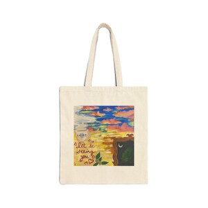 May include: A white tote bag with a colorful painting of a sky with clouds, a teacup, and a framed image of a moon and trees. The text "I'll be seeing you" is written in red on the bag.