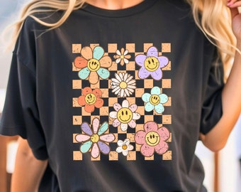 May include: Black t-shirt with a checkered pattern and colorful flowers with smiley faces.