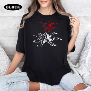 May include: Black t-shirt with a white graphic of a mountain and a red dragon flying above it.