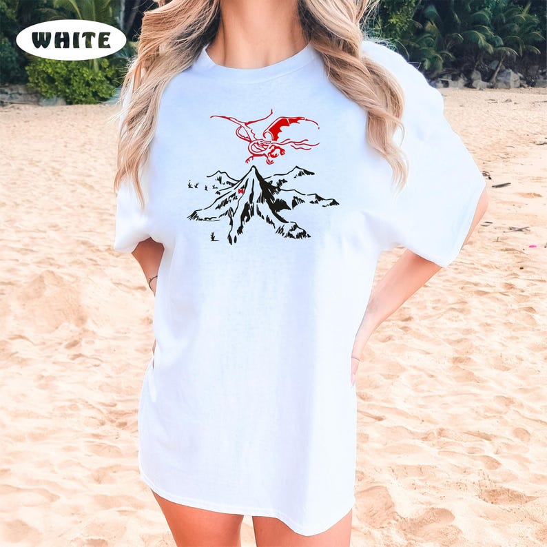May include: White t-shirt with a black and red graphic of a dragon flying over a mountain range. The text "WHITE" is in the top left corner of the image.