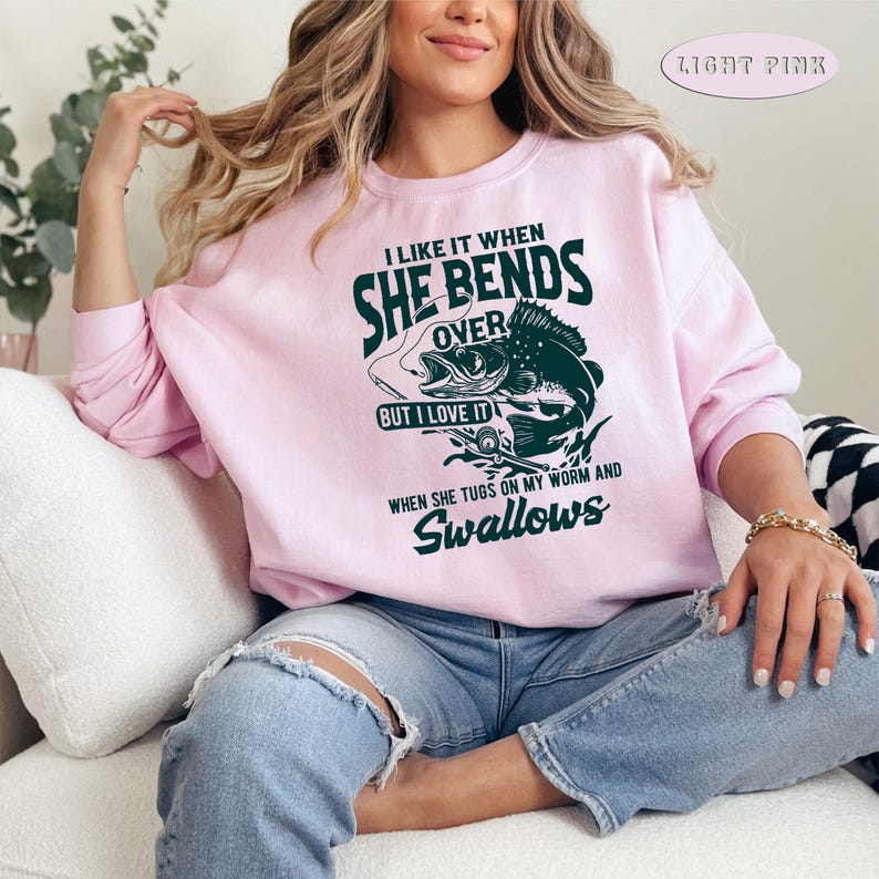 May include: Light pink sweatshirt with a fishing-themed graphic that says "I like it when she bends over but I love it when she tugs on my worm and swallows".