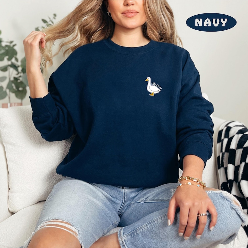 May include: A navy blue sweatshirt with a white goose graphic and the text "Silly Goose" on the left chest.