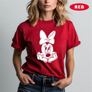 May include: Red t-shirt with a white graphic of Minnie Mouse with a bow.