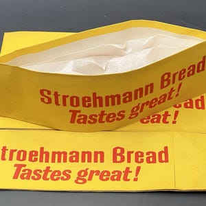 May include: Yellow Stroehmann Bread paper hats with red text reading "Stroehmann Bread Tastes great!" The hats are folded and have a white interior. The image shows several hats.