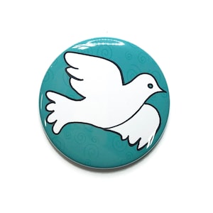 May include: A round button with a white dove illustration against a teal background. The dove is outlined in black and has a small black eye. The teal background features a subtle swirl pattern.