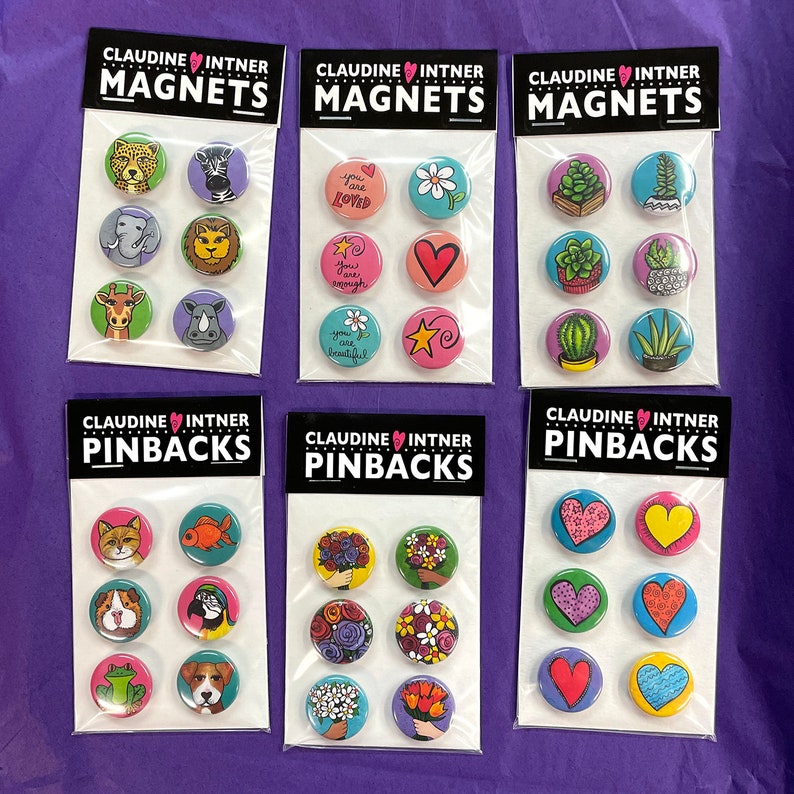 May include: Six sets of colorful, round pinback buttons and magnets with various designs. The top row features animal, nature, and inspirational quotes. The bottom row features animal, floral, and heart designs. Each set is packaged in a clear plastic bag with a white label that reads "CLAUDINE INTNER" and either "MAGNETS" or "PINBACKS".