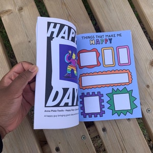 May include: An open book with a blue cover and the text "THINGS THAT MAKE ME HAPPY" on the front. The book has several blank spaces for writing or drawing.