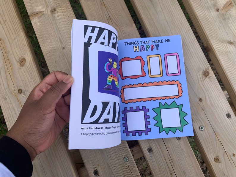 May include: An open book with a blue cover and the text "THINGS THAT MAKE ME HAPPY" on the front. The book has several blank spaces for writing or drawing.