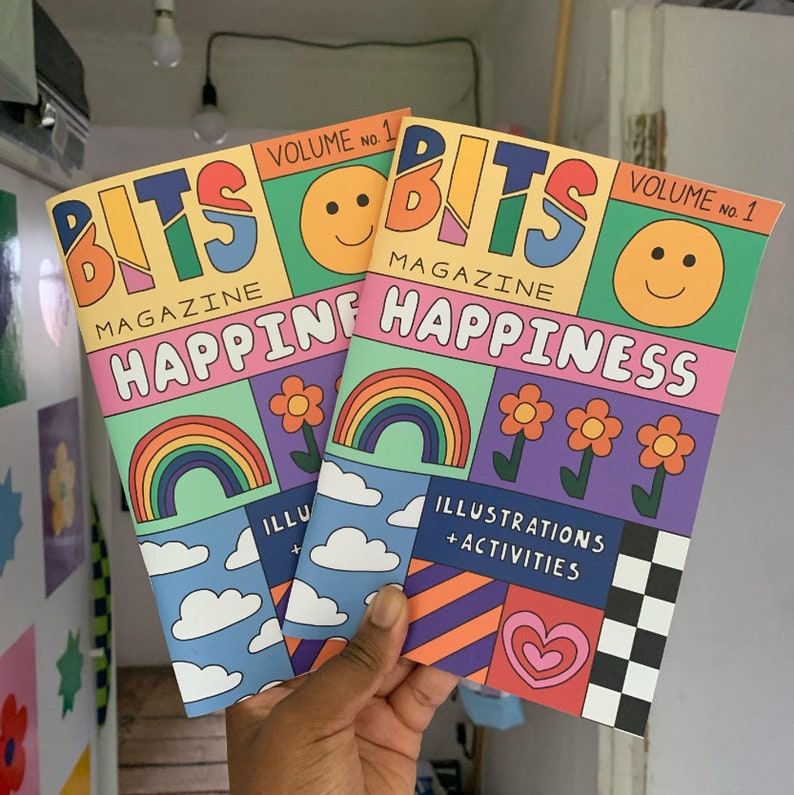 May include: Two colorful magazines titled "BITS MAGAZINE HAPPINESS" with illustrations of rainbows, clouds, hearts, and smiley faces. The magazines are volume 1.