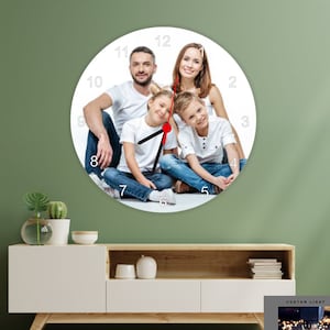 May include: A round wall clock featuring a family portrait. The clock face displays a photo of a smiling family of four. Black clock hands point to the time. The clock is a decorative piece for home decor.