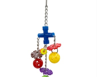 May include: A colorful bird toy with a blue cross-shaped top, connected to a chain. The chain supports various plastic shapes, including red and purple flower-like pieces, yellow and red balls, and brown gear-shaped pieces. The toy is designed for birds.
