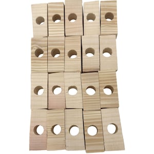 Puede incluir: Un conjunto de pequeños bloques de madera rectangulares con un acabado natural de vetas. Cada bloque tiene un agujero circular perforado en el centro. Los bloques están dispuestos en un patrón ligeramente superpuesto.